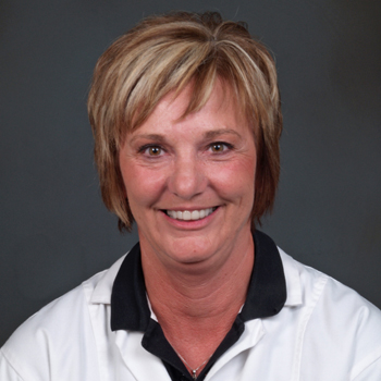 Team member Linda wearing a white lab coat over a black polo shirt